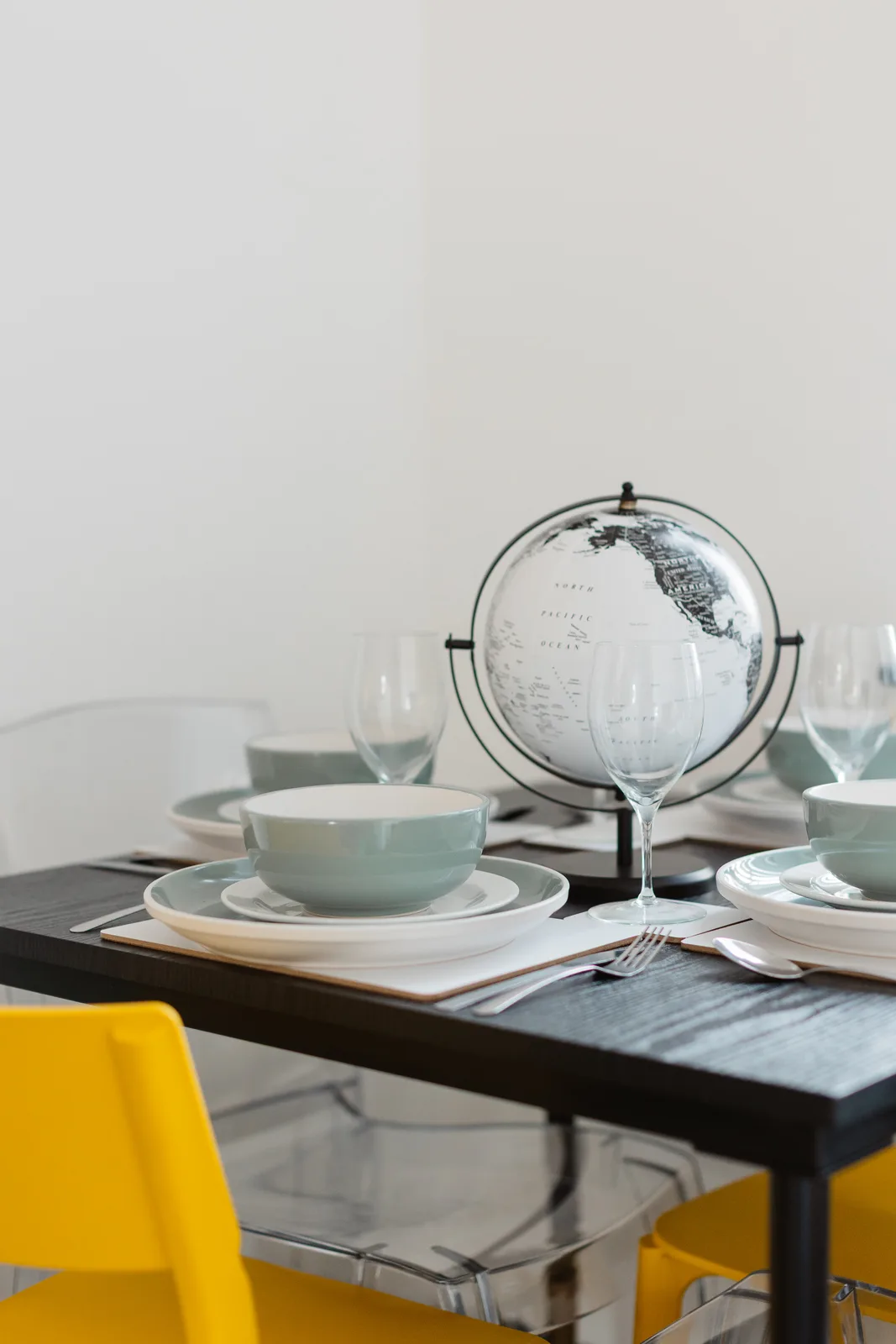 Widnes dining table with crockery, glassware, a globe centrepiece and yellow chairs