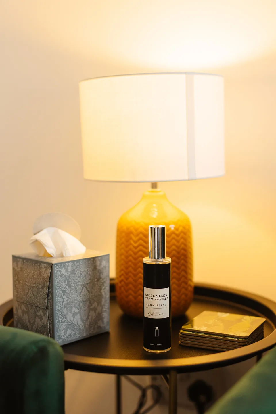 Lamp and thoughtful room details beside an emerald-green velvet sofa at the Widnes home