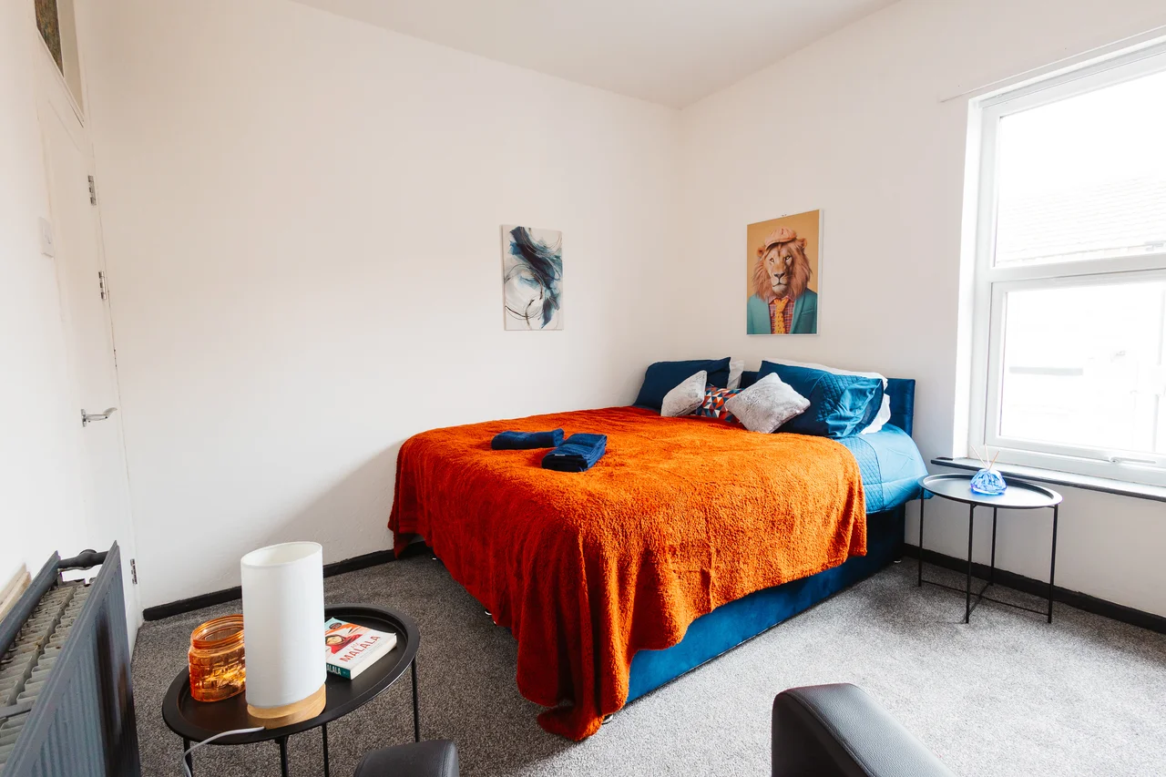 Widnes bedroom with orange and blue bedding, a large window and a bedside table