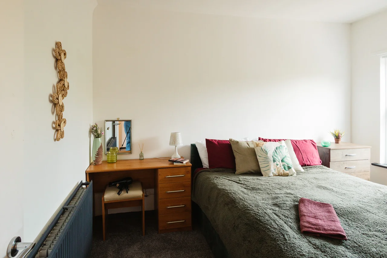 Widnes bedroom with sage bedding, burgundy cushions, a wooden dressing table and hare artwork